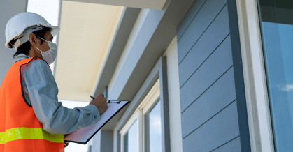 A site inspector in hi-vis with a clipboard, checking a window on a newly built home