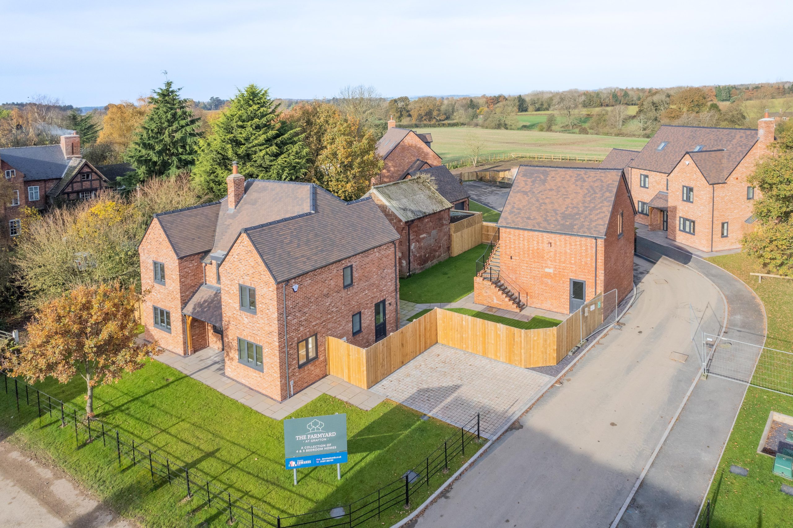The detached homes at The Farmyard in Grafton seen from above, with gardens and fields behind