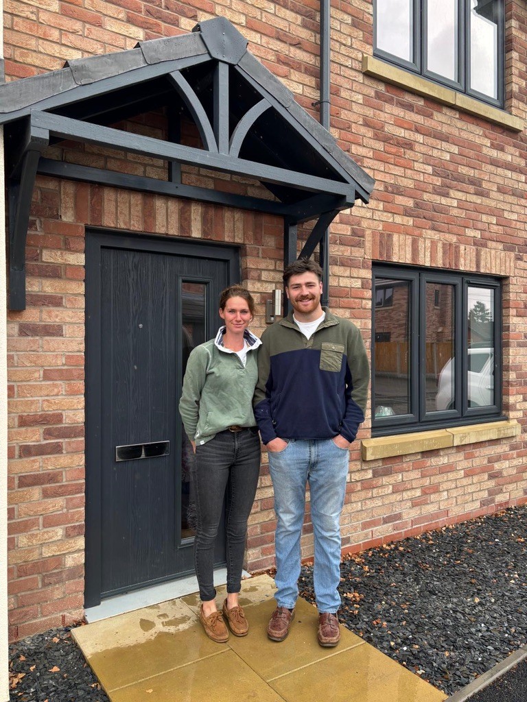 Kathy and Edward standing outside the front door of the first completed home at The Mulberries at Dudleston Heath